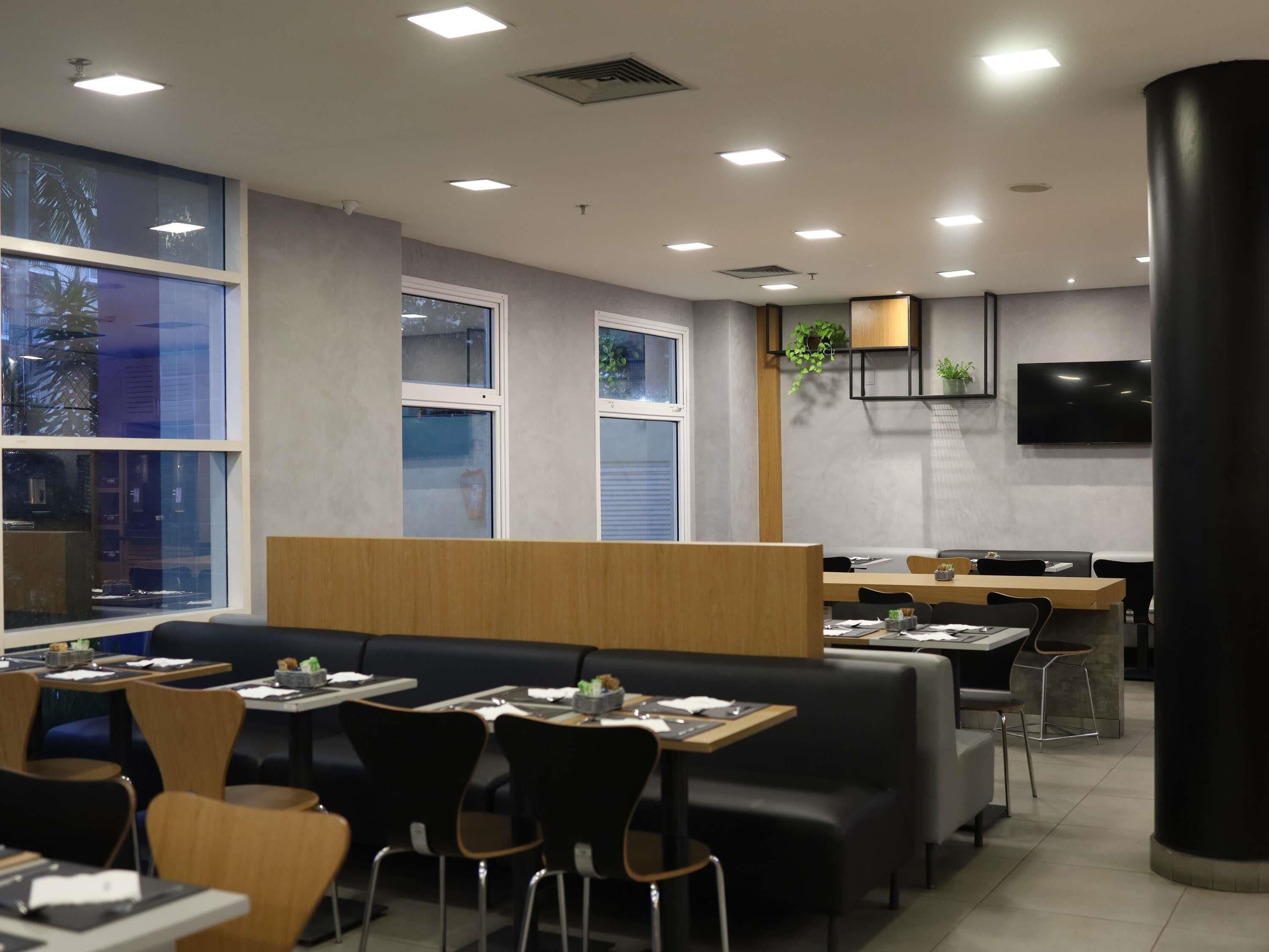 Un restaurante moderno con una barra larga, cabinas y un televisor en la pared.