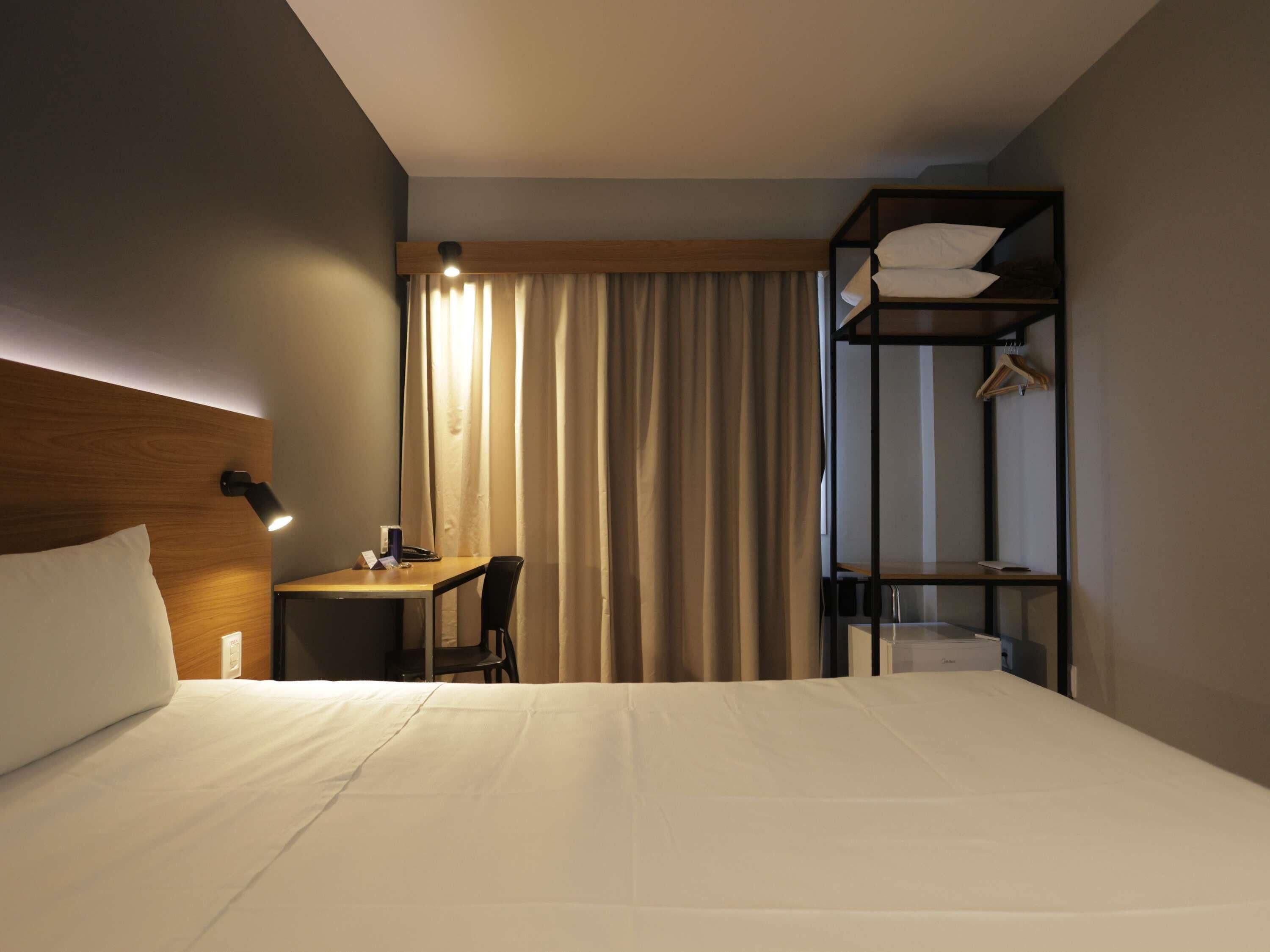 Una habitación de hotel con cama, escritorio, silla y armario empotrado.