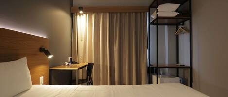 Una habitación de hotel con cama, escritorio, silla y armario empotrado.