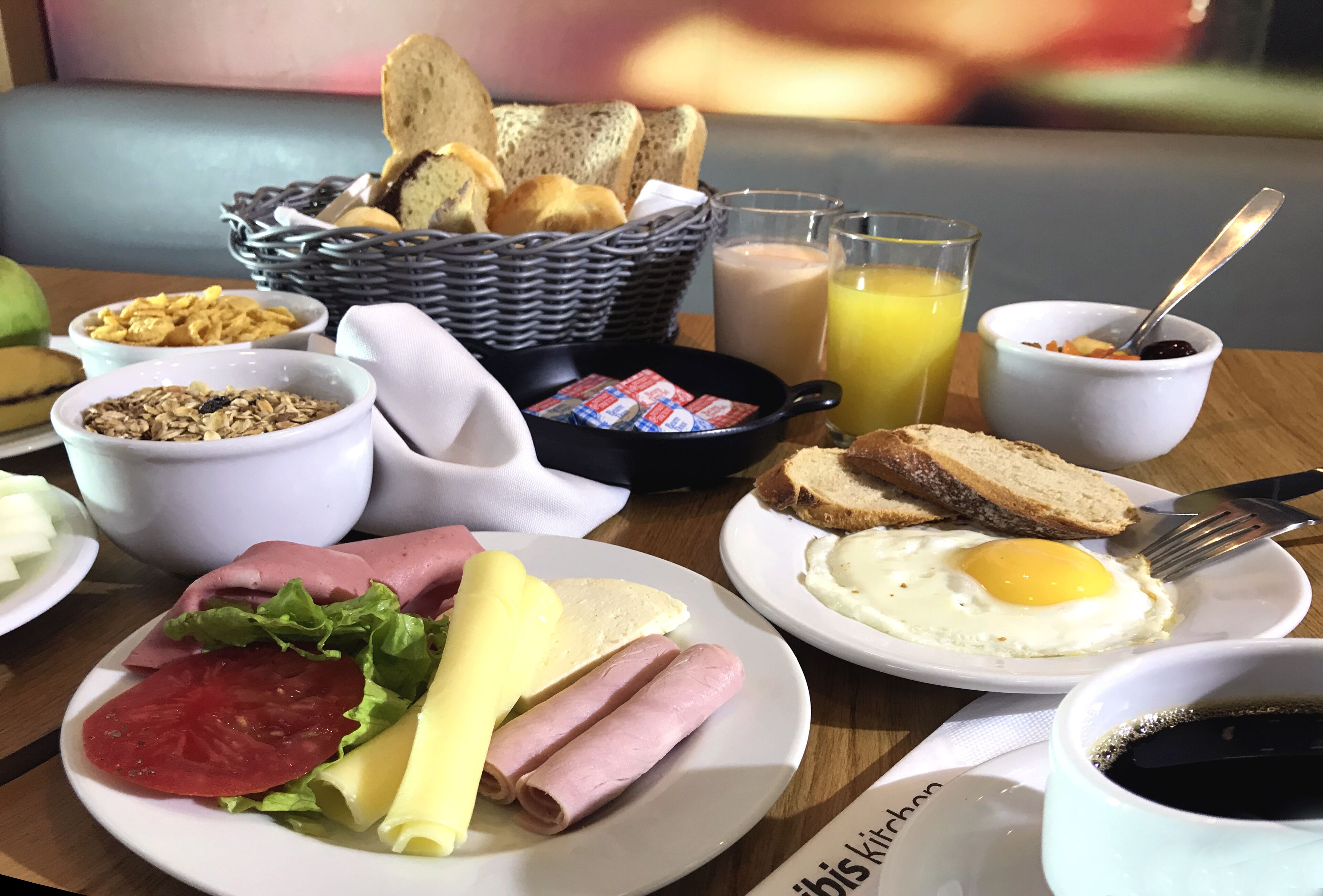 A breakfast table with various food items, including eggs, bread, and a basket of rolls.