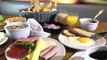Uma mesa de café da manhã com diversos alimentos, incluindo ovos, pão e uma cesta de pães.