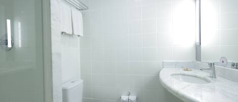 A bathroom with a toilet, sink, and mirror.