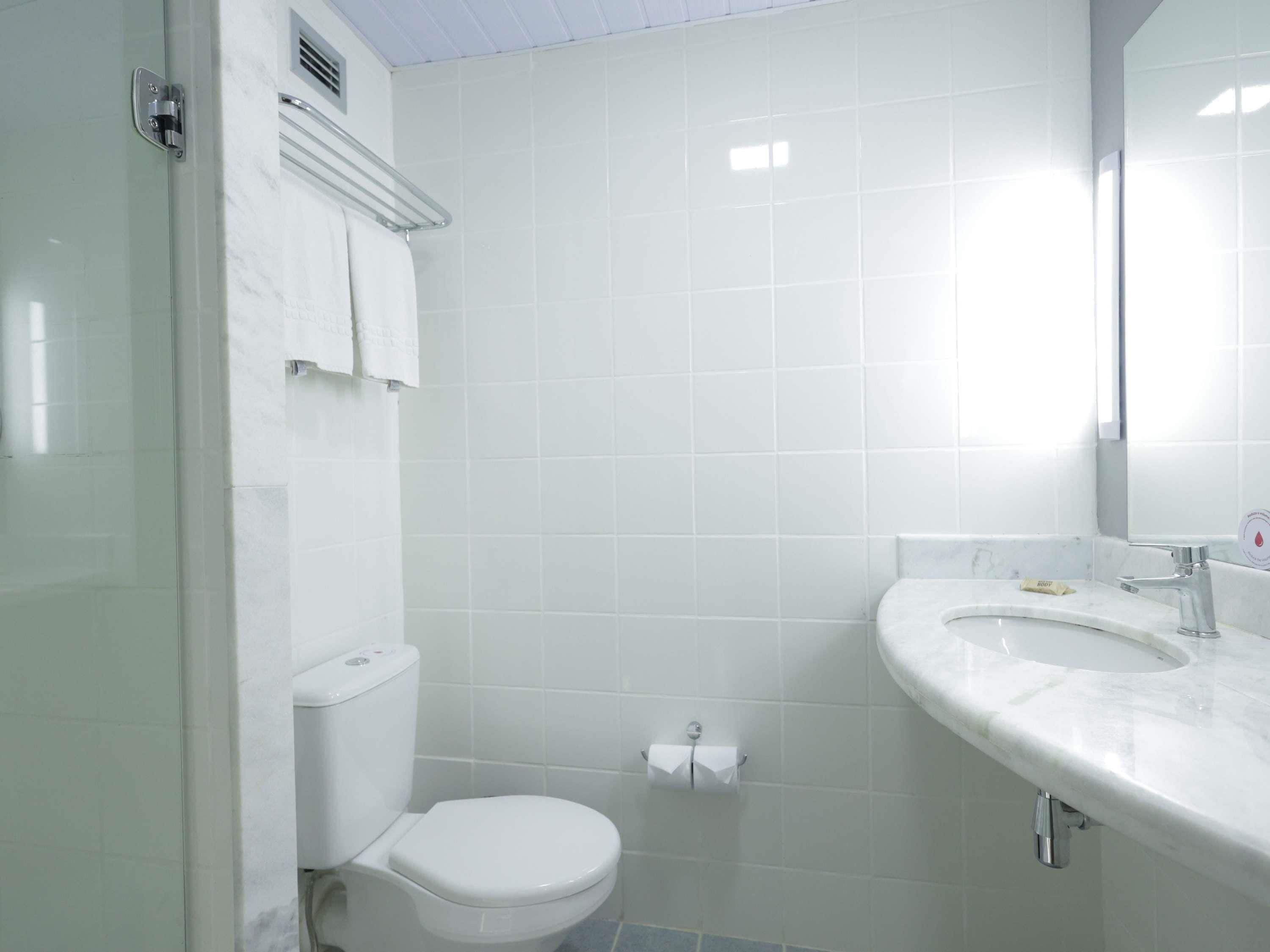 A bathroom with a toilet, sink, and mirror.