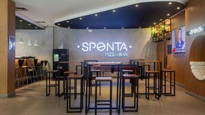 Un bar à pizzas appelé SPONTA, doté d’un espace pour s’asseoir et d’un écran numérique affichant le menu.