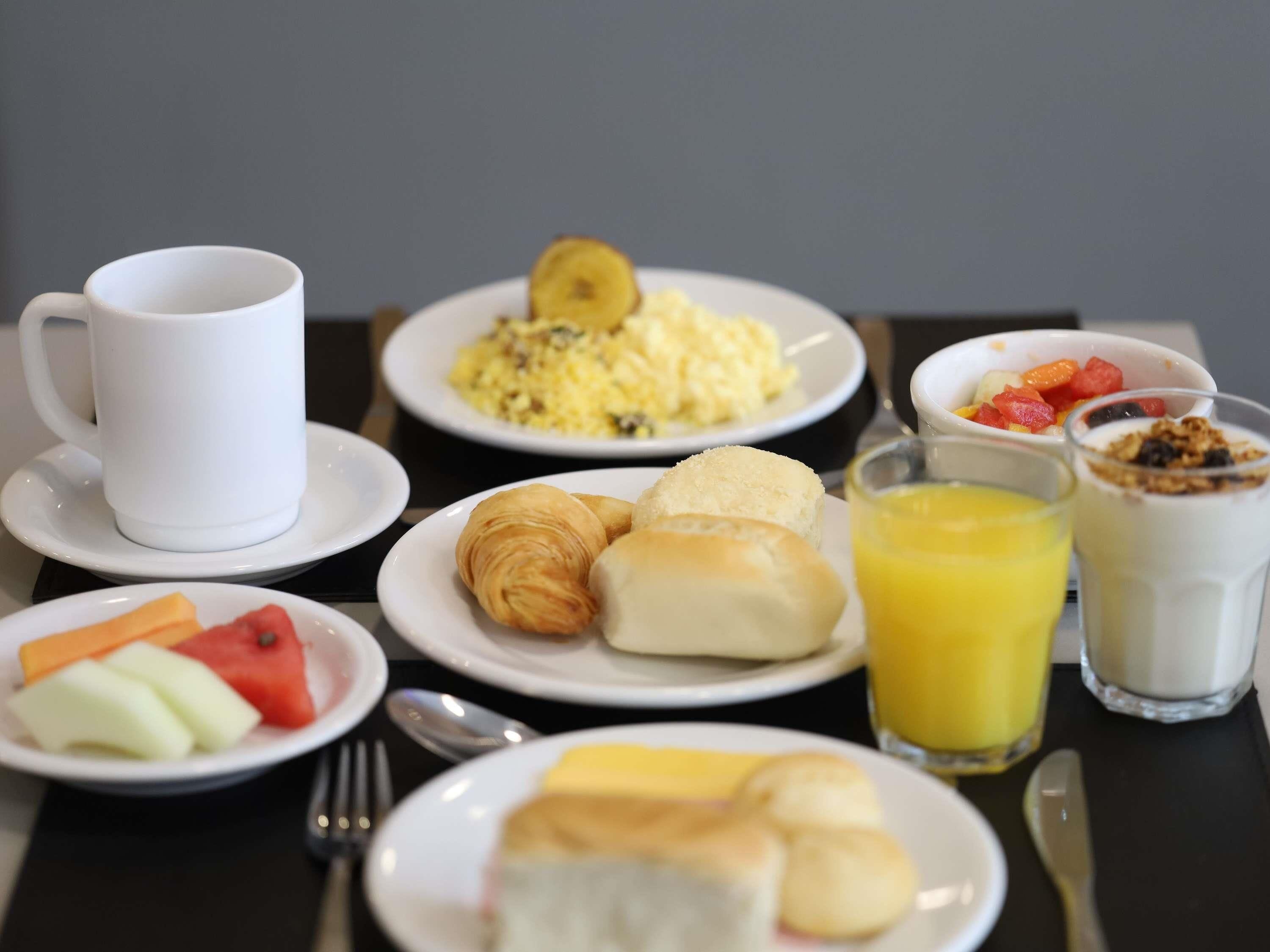 A breakfast setting with plates of food, a cup, and a glass of juice.