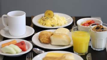 Une table mise pour le petit-déjeuner, avec des assiettes remplies de nourriture, une tasse et un verre de jus.