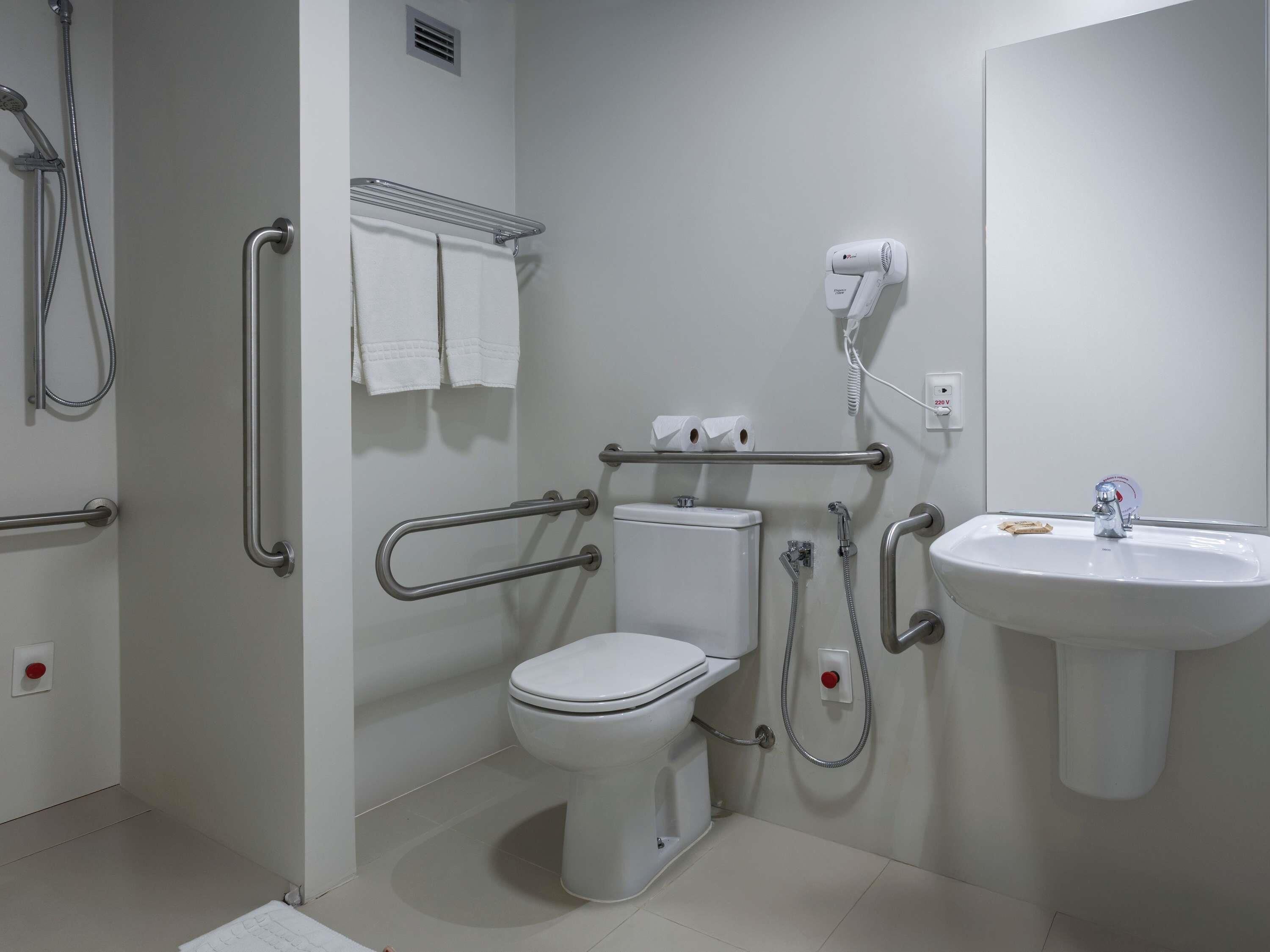 A bathroom with a toilet, bidet, hand dryer, and a sink.