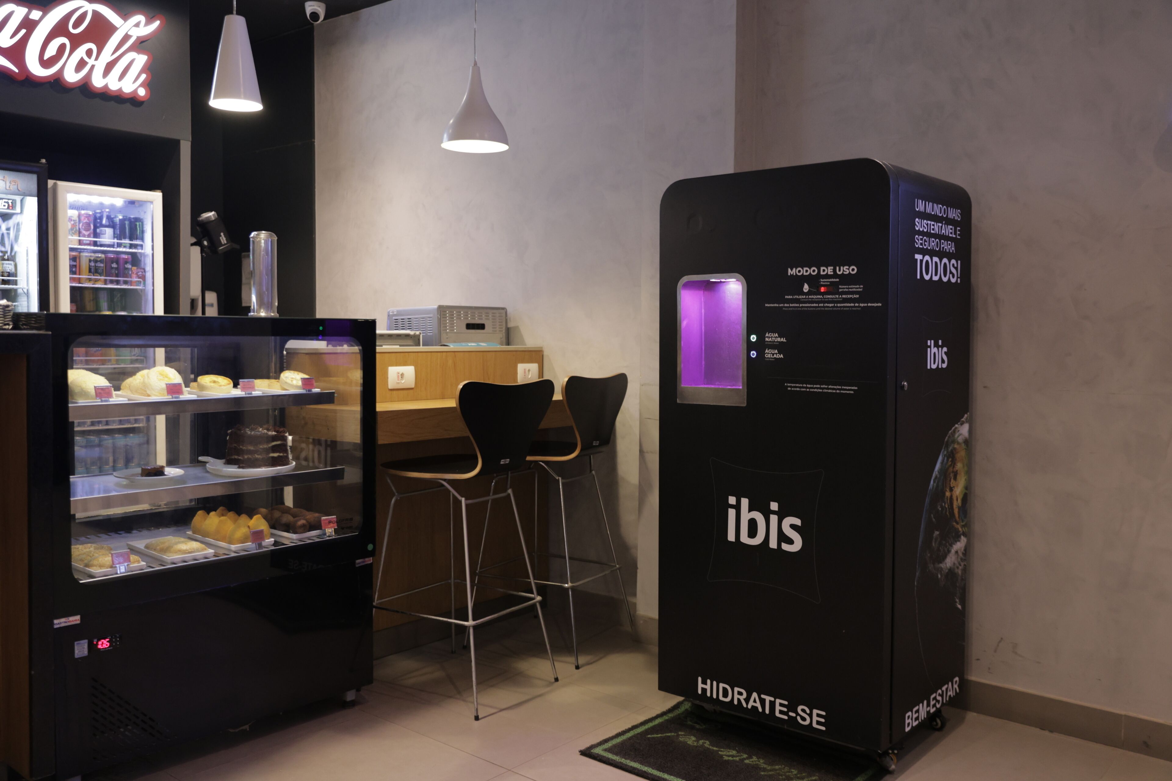 Un distributeur de boissons éclairé d’une lumière violette, un présentoir rempli de pâtisseries et une enseigne Coca-Cola.