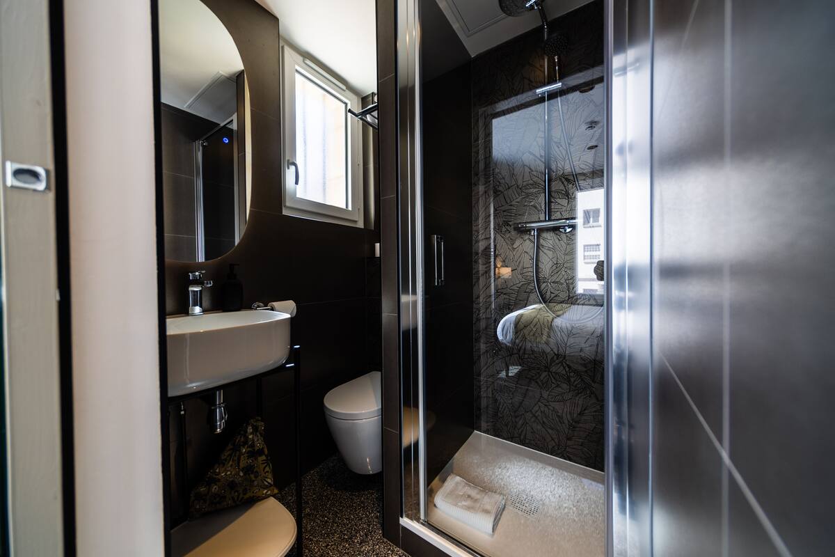A modern bathroom with a glass shower enclosure, a toilet, and a sink.