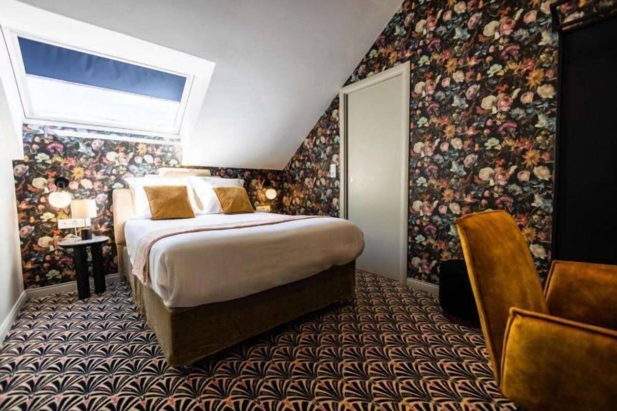 A bedroom with a bed, a small table, a chair, and a window.