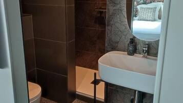 A modern bathroom with a toilet, sink, and shower.