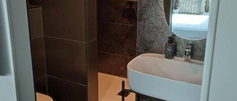 Un baño moderno con inodoro, lavamanos y ducha.