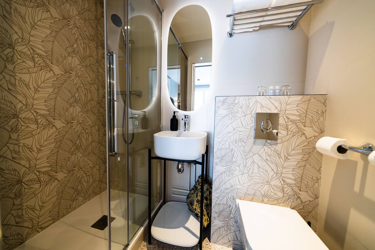 A modern bathroom with a glass shower enclosure, a white sink, and a toilet.