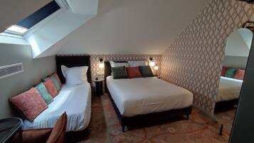 Une chambre d’hôtel avec deux lits, une petite table, une chaise, un miroir et un mur décoré d’un motif.