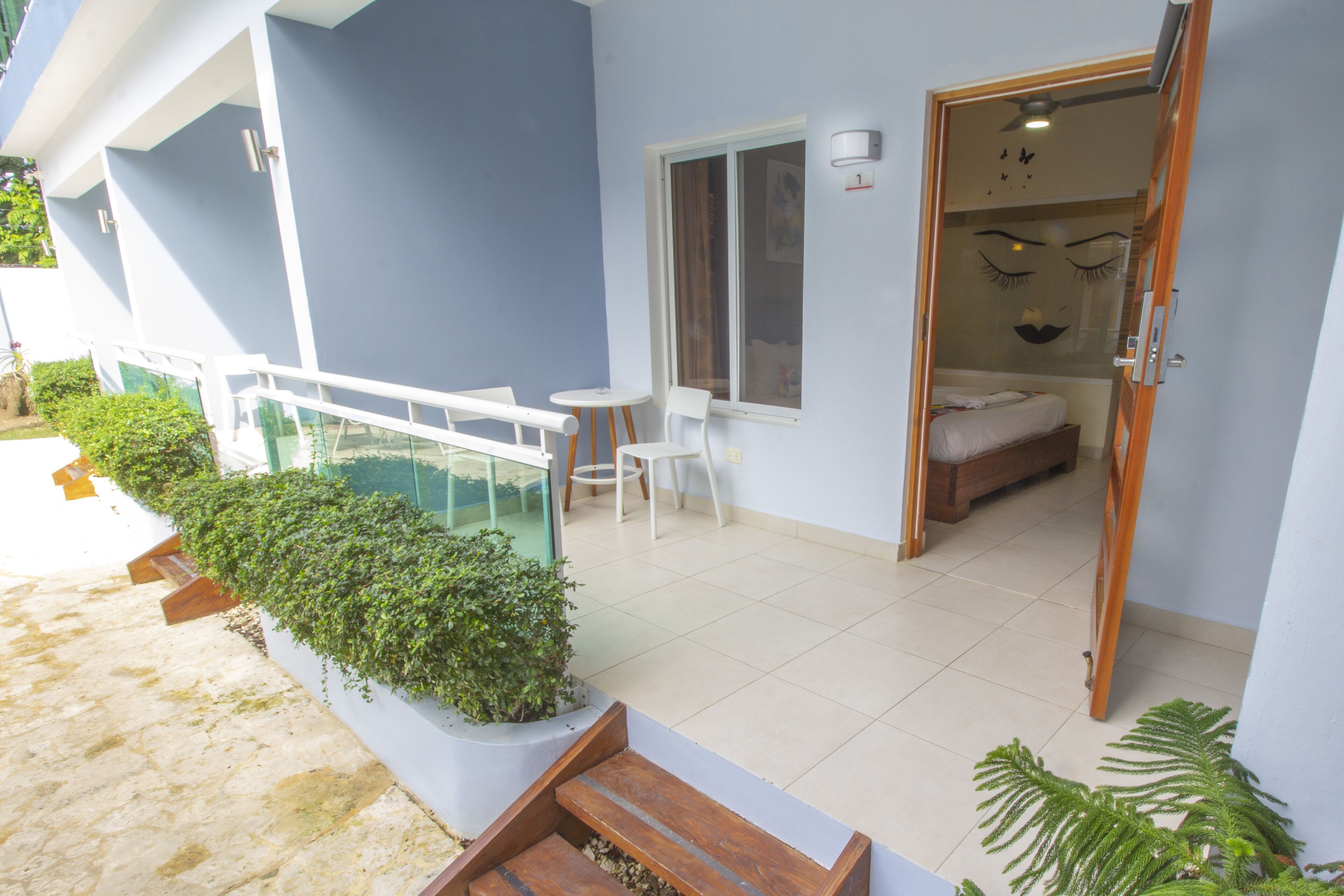 A modern hotel room with a balcony, a small table and chairs, and a bed.