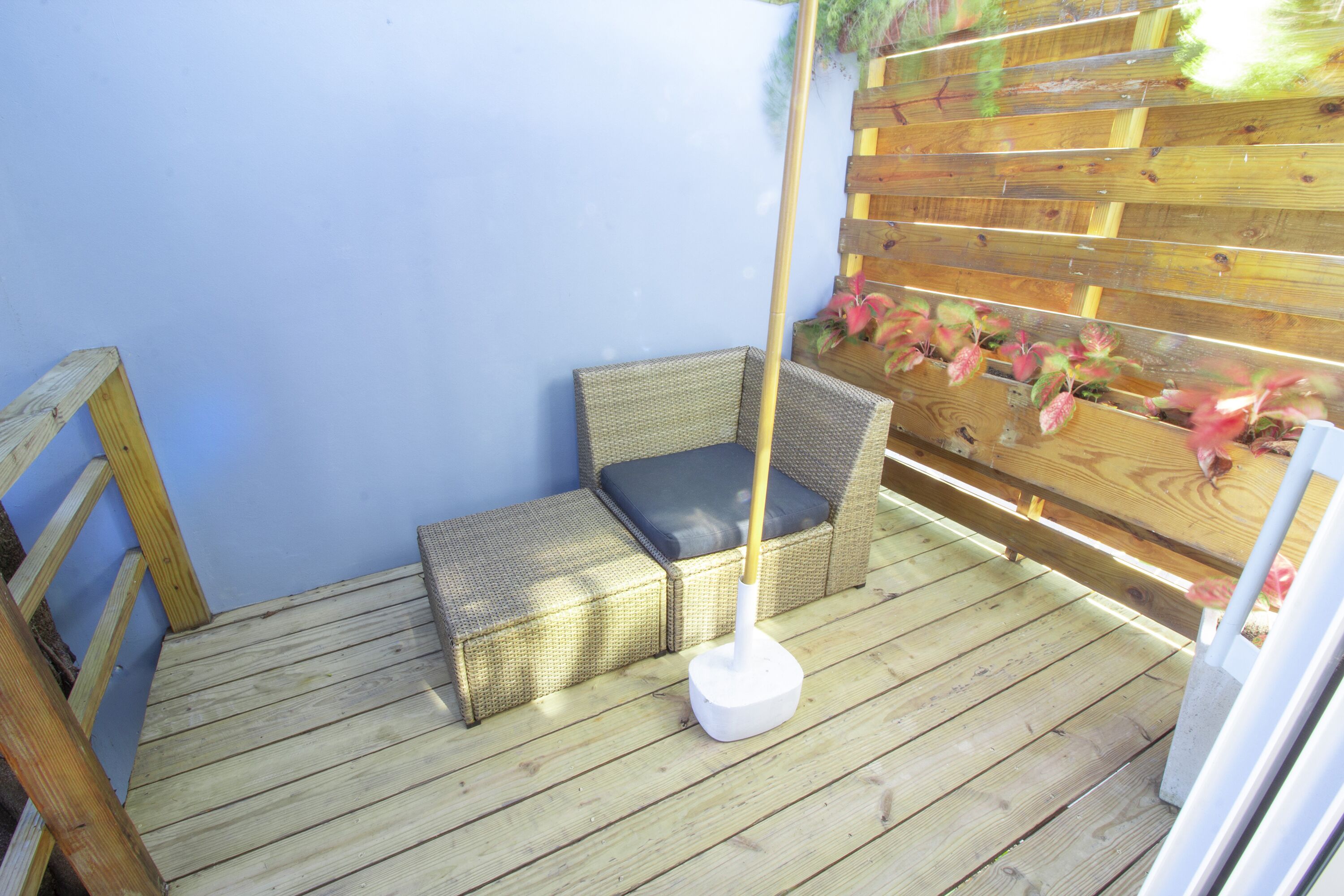A wooden deck with wicker furniture and a white pole.