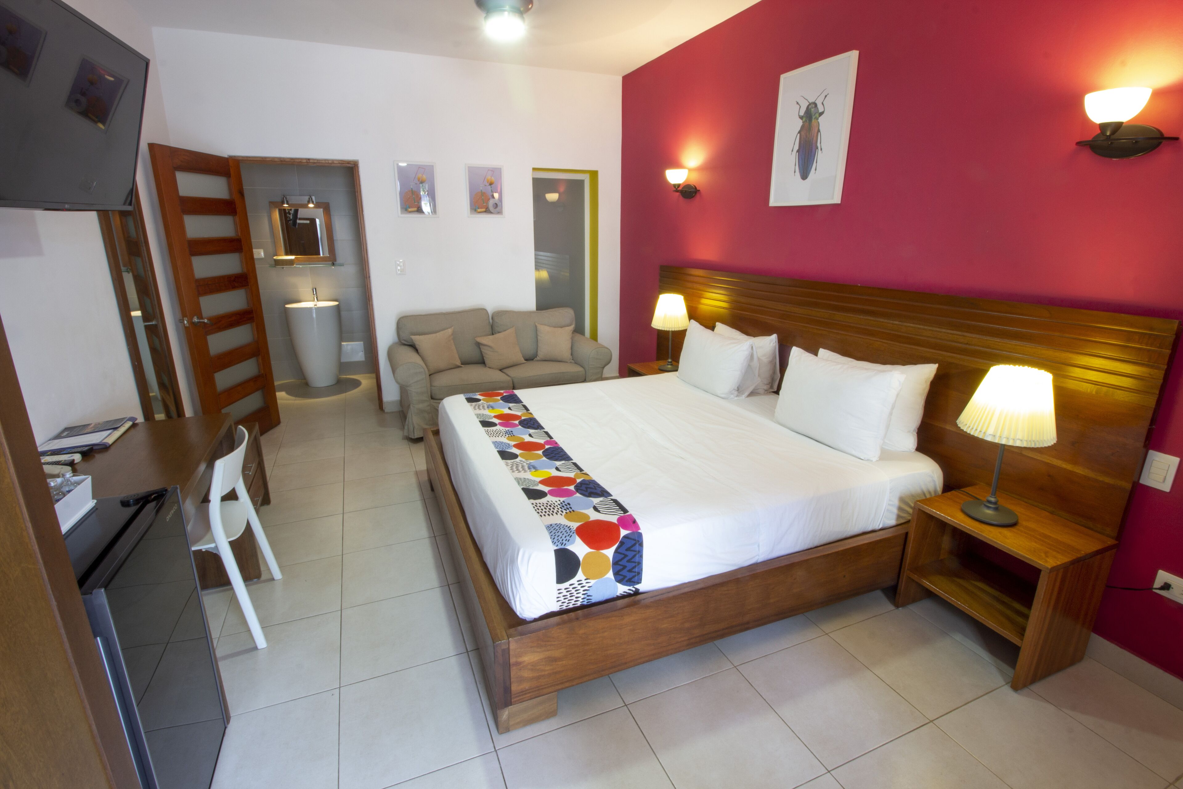 Una habitación de hotel con cama, mesitas de noche, escritorio, silla y baño.