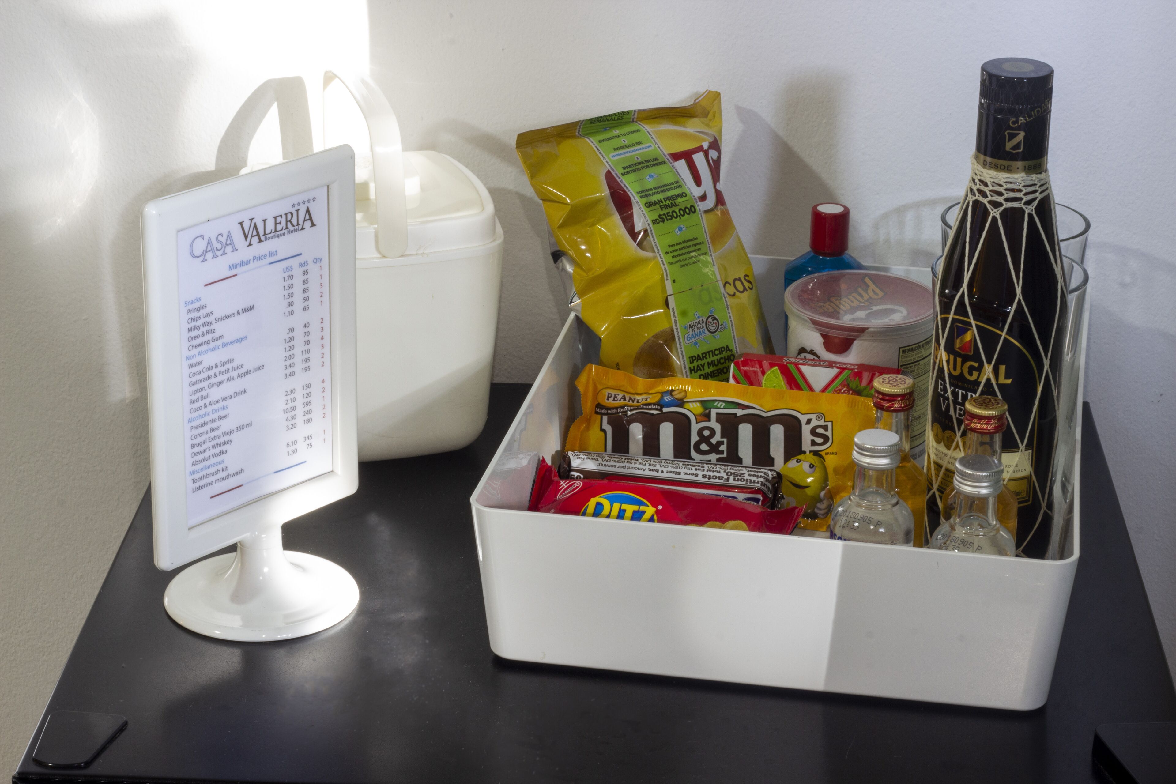 A minibar with snacks, drinks, and a computer monitor displaying a price list.