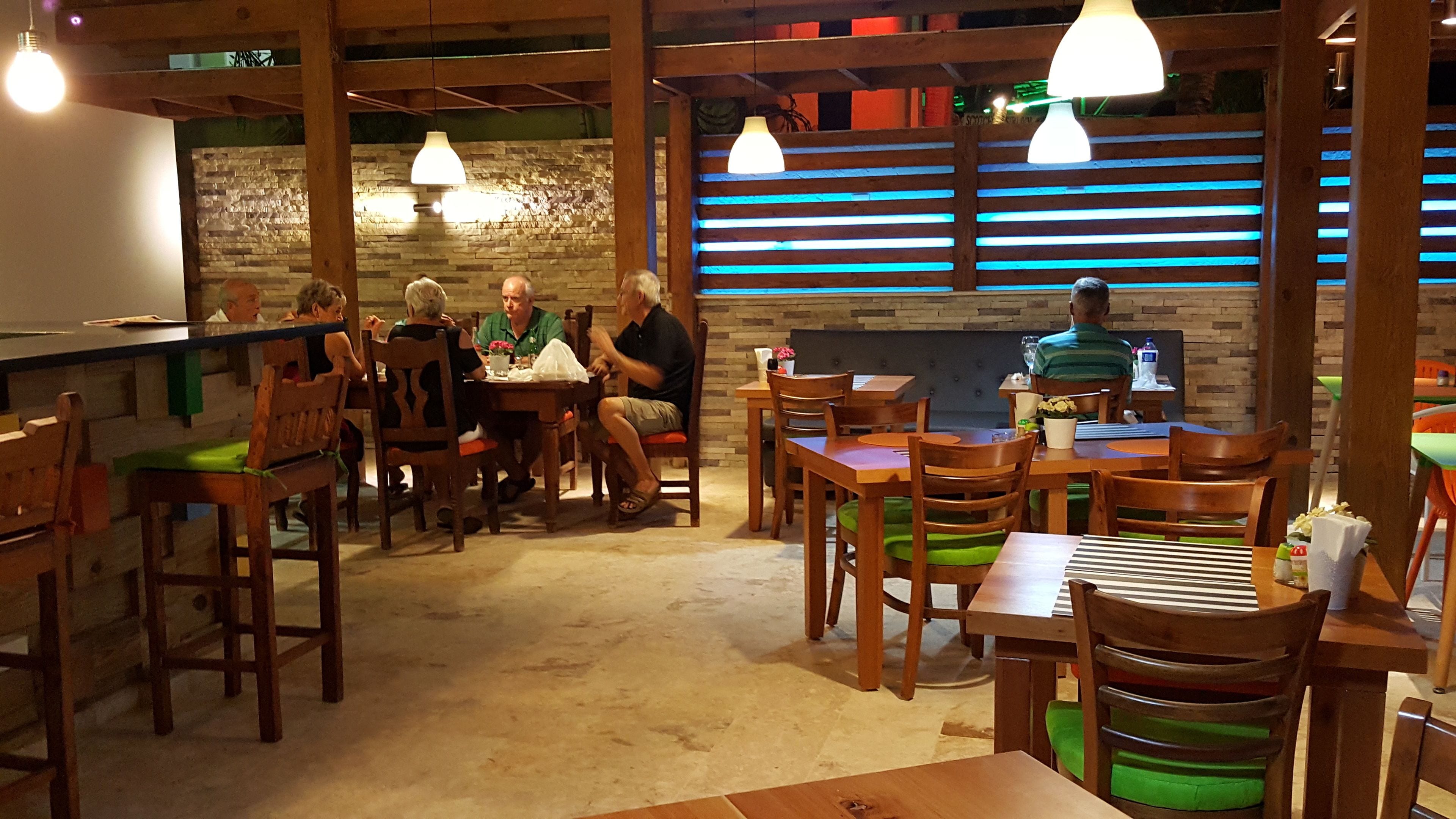 Un restaurant avec des meubles en bois et un mur en pierre. Les tables et les chaises sont disposées pour accueillir les clients.