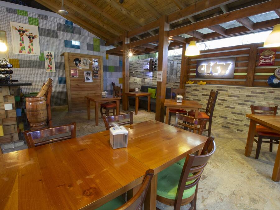 Een restaurant interieur met houten tafels en stoelen, een bakstenen muur en een bord met de tekst 'City7'.