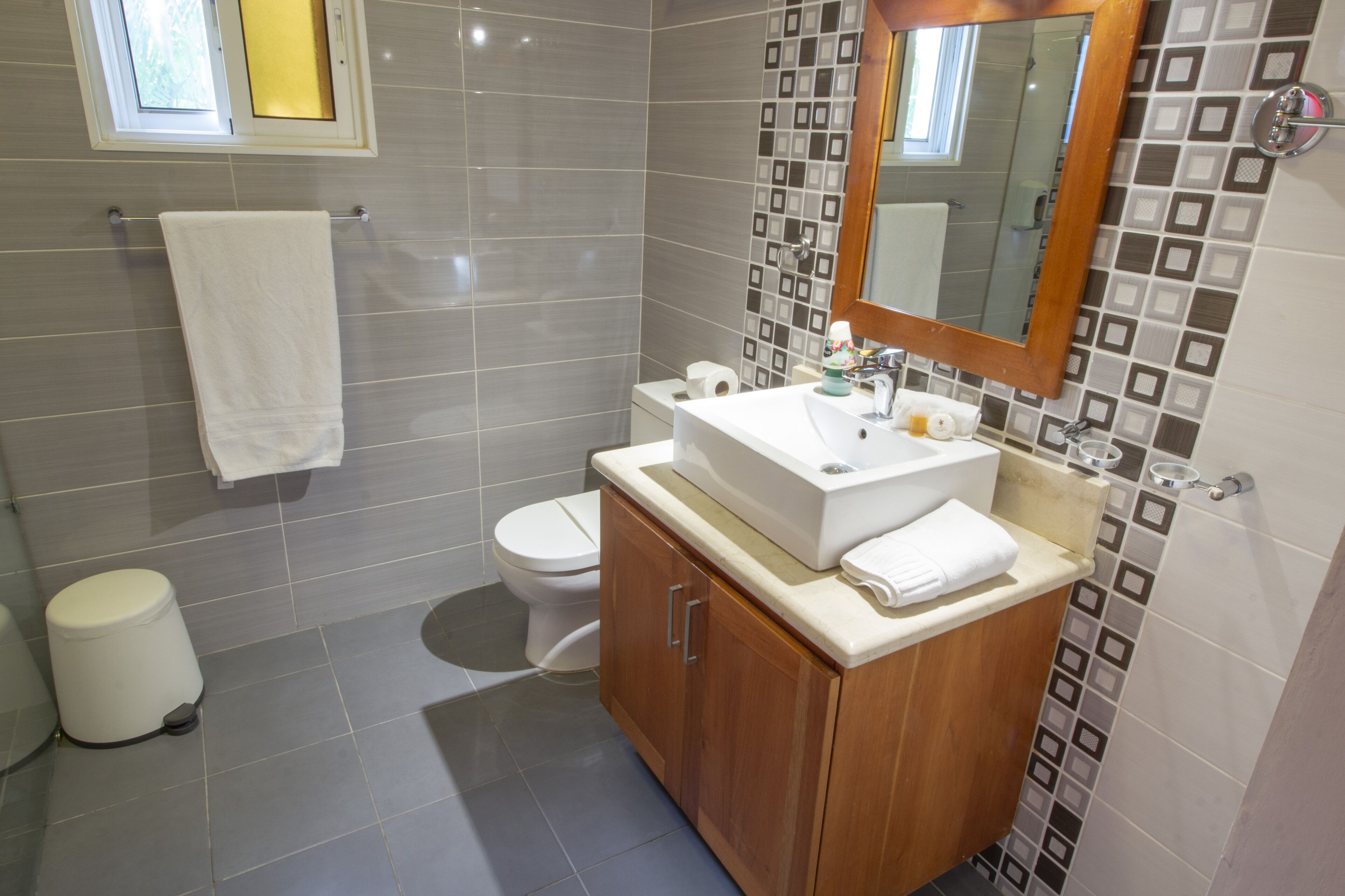 A modern bathroom with a large mirror, a sink, and a toilet.