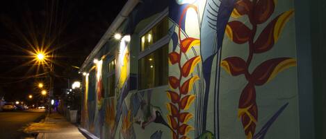 A building with colorful murals of birds and plants on its exterior wall.