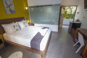 Un dormitorio moderno con una cama grande, un escritorio y vistas a un balcón con plantas.