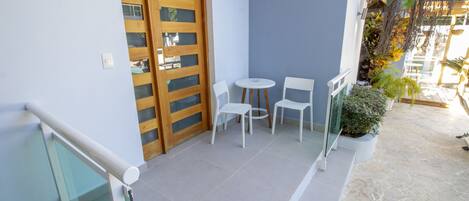 A balcony with a glass railing, a wooden door, and a small table with two chairs.