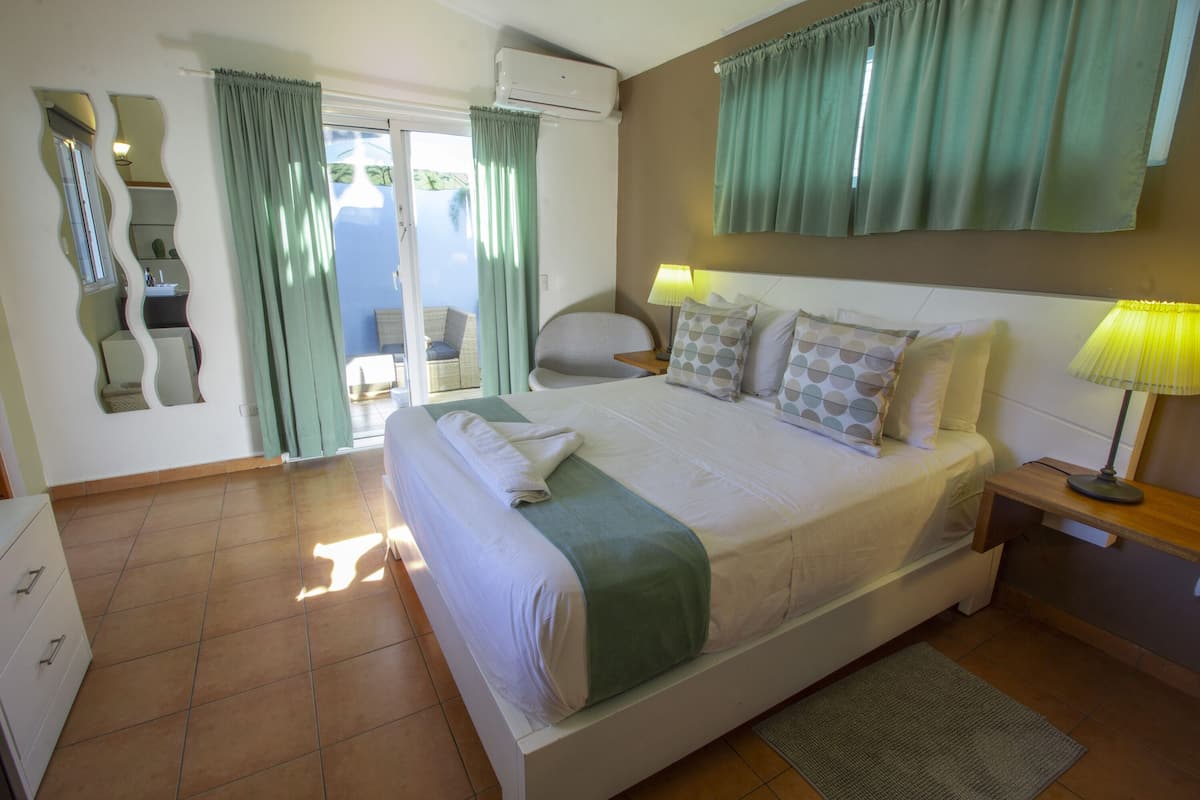 Ein Schlafzimmer mit Bett, Schreibtisch, Stuhl, Spiegel und einem Fenster mit Vorhängen.