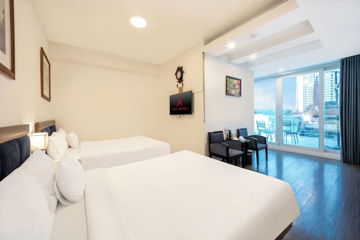 A hotel room with two beds, a desk, and a large window with a city view.