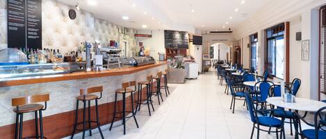 A restaurant with a bar area, seating, and a menu board.