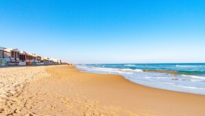 A beach with a row of buildings along the shore.