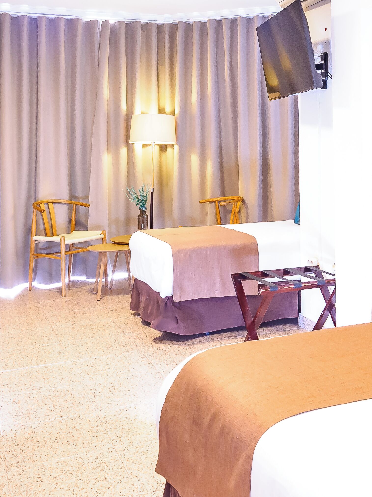 Une chambre d’hôtel avec deux lits, un bureau, une chaise, une lampe et un téléviseur.
