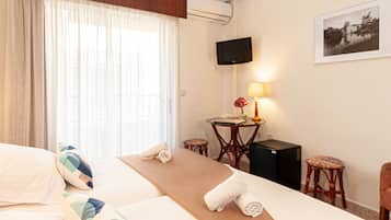 A hotel room with a bed, a desk with a lamp, a chair, and a TV on the wall.