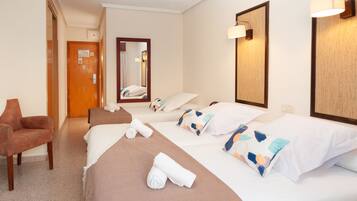 Una habitación de hotel con una cama, una silla, un espejo y una puerta.