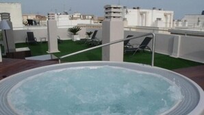 A hot tub on a rooftop terrace with a view of the cityscape.