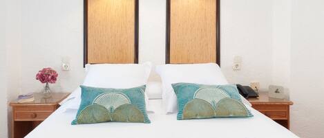 Une chambre d’hôtel avec un grand lit, deux tables de chevet et une petite table d’appoint.