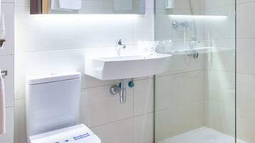 Een moderne badkamer met toilet, wastafel en douchecabine.