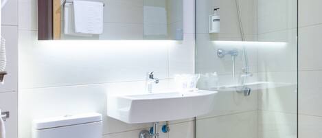 A modern bathroom with a toilet, sink, and glass-enclosed shower.