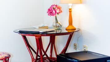 Una habitación pequeña con una mesa, una lámpara, un televisor y un refrigerador.