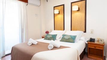 A hotel room with a bed, two bedside lamps, a nightstand, and a telephone.