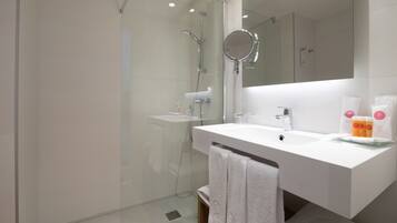 Un baño moderno con ducha envuelta en vidrio, un lavabo blanco y un espejo grande.