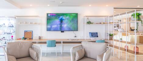 A modern living room with a flat-screen TV, two sofas, a coffee table with a cactus, and a bookshelf.