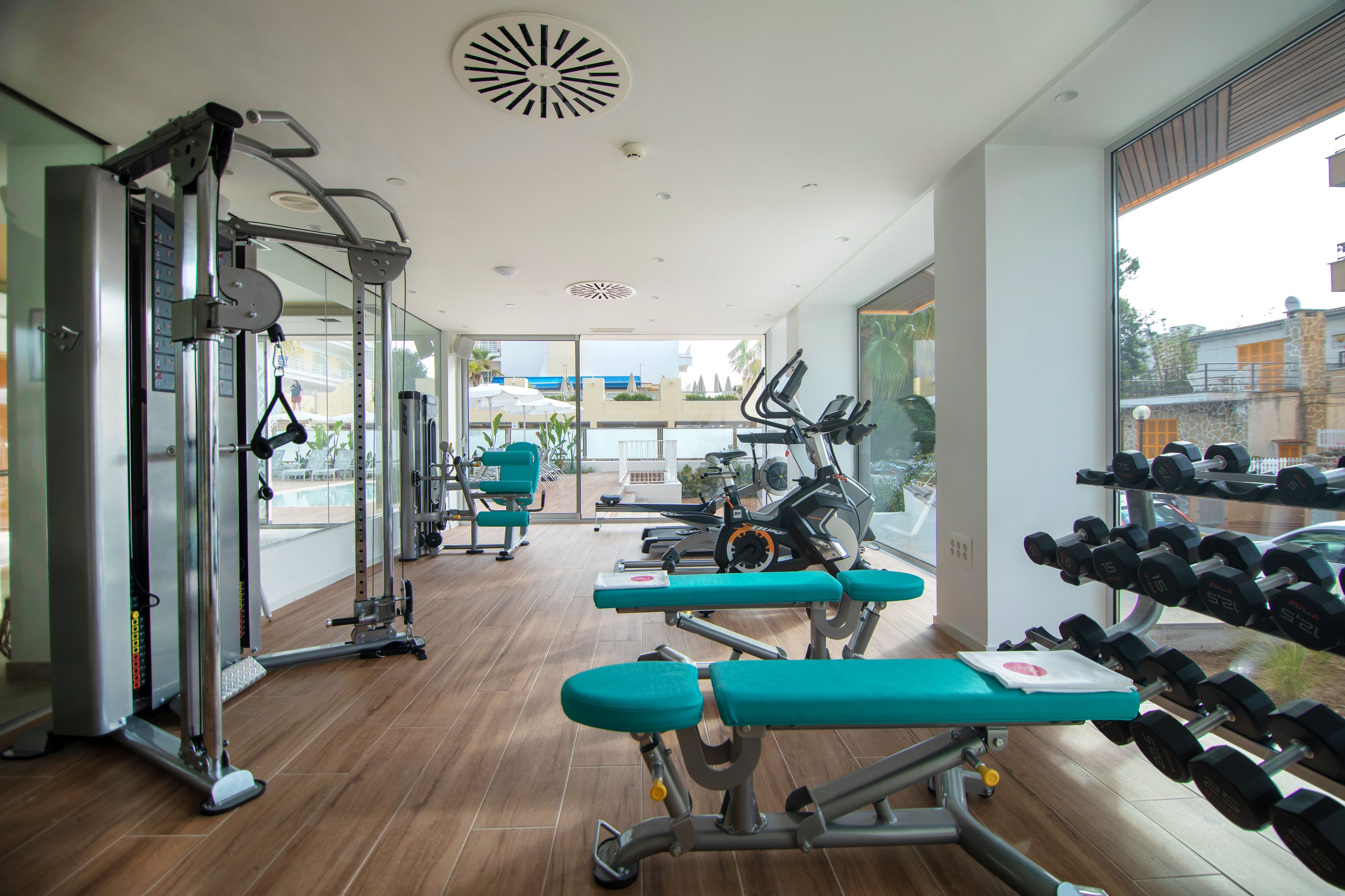 A gym with exercise equipment, benches, and dumbbells.