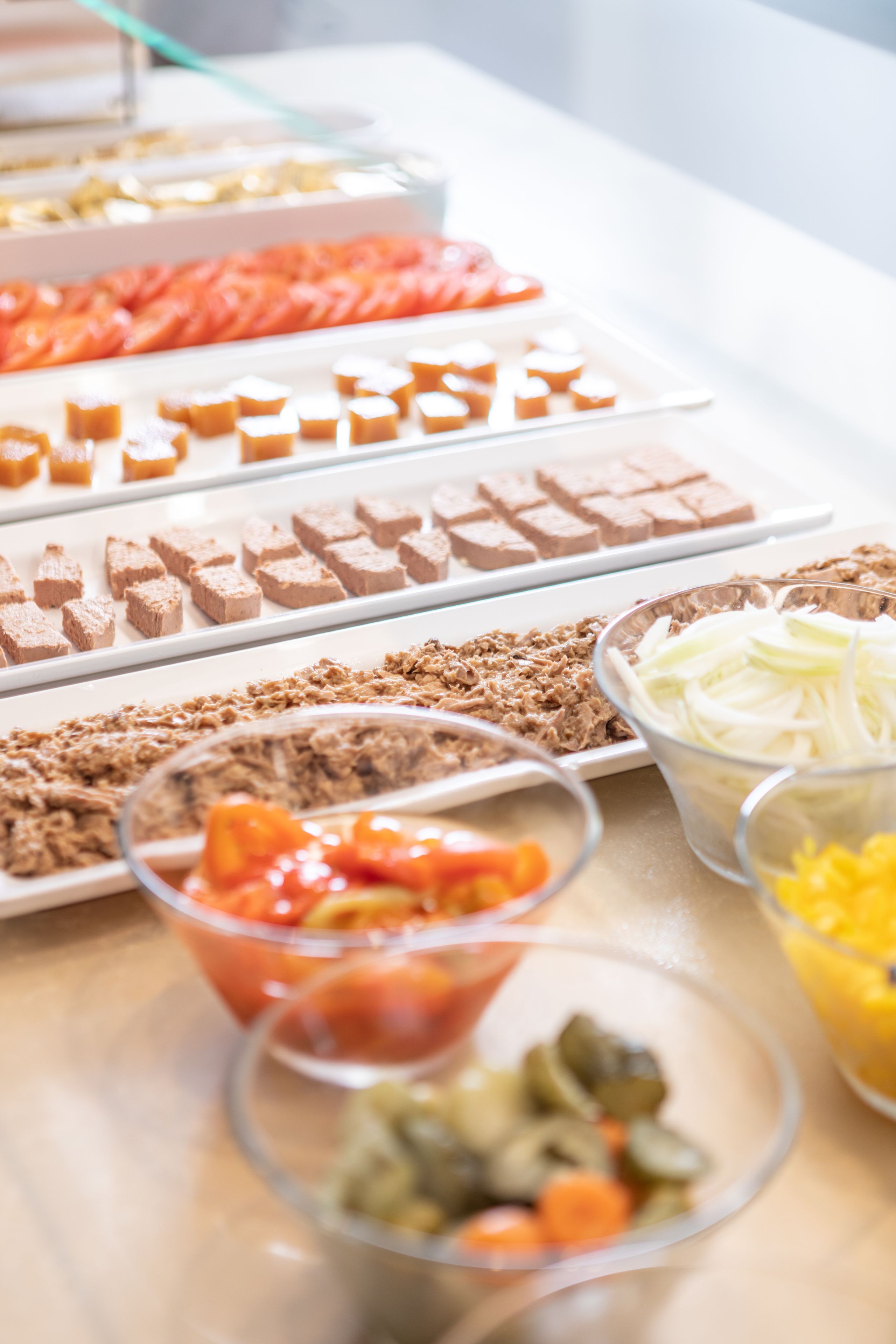 Una mesa de buffet con diversos alimentos, como embutidos, quesos y verduras.
