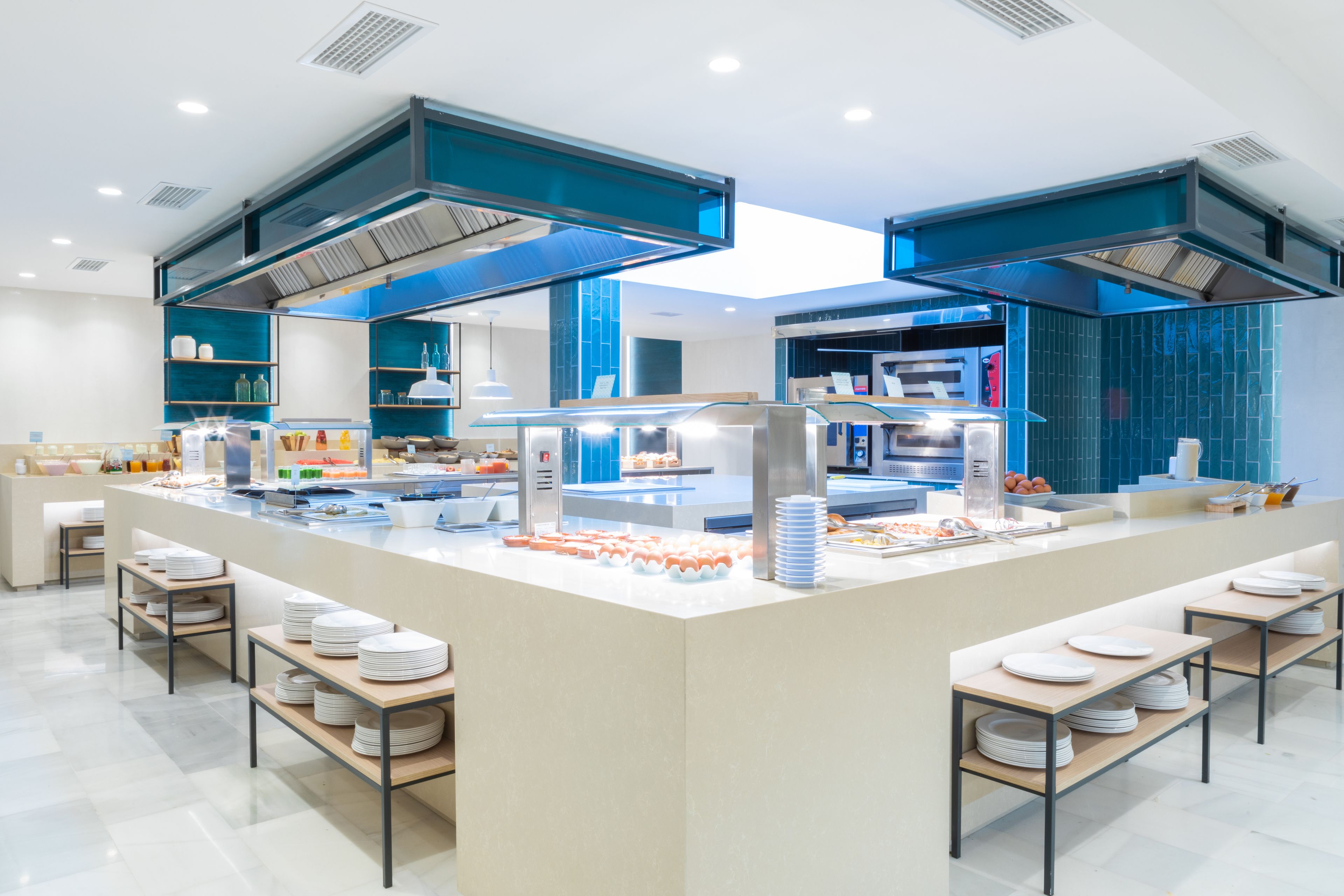Een moderne keuken met een centraal kookeiland, inbouwapparatuur en een blauwe tegelachterwand.