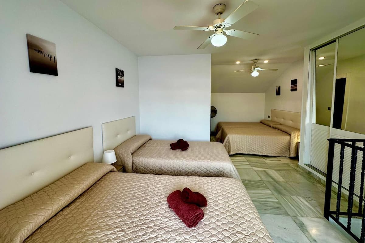 Een hotelkamer met twee bedden, een plafondventilator en een grote spiegel.