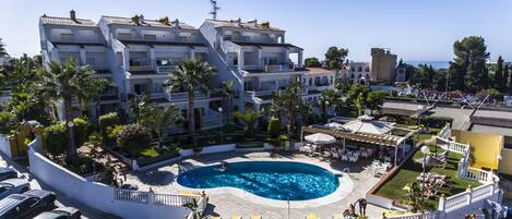 A hotel with a pool, multiple balconies, and a view of the sea.