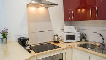 Een koelkast met diepvriezer, een microgolfoven, een oven, een kookplaat