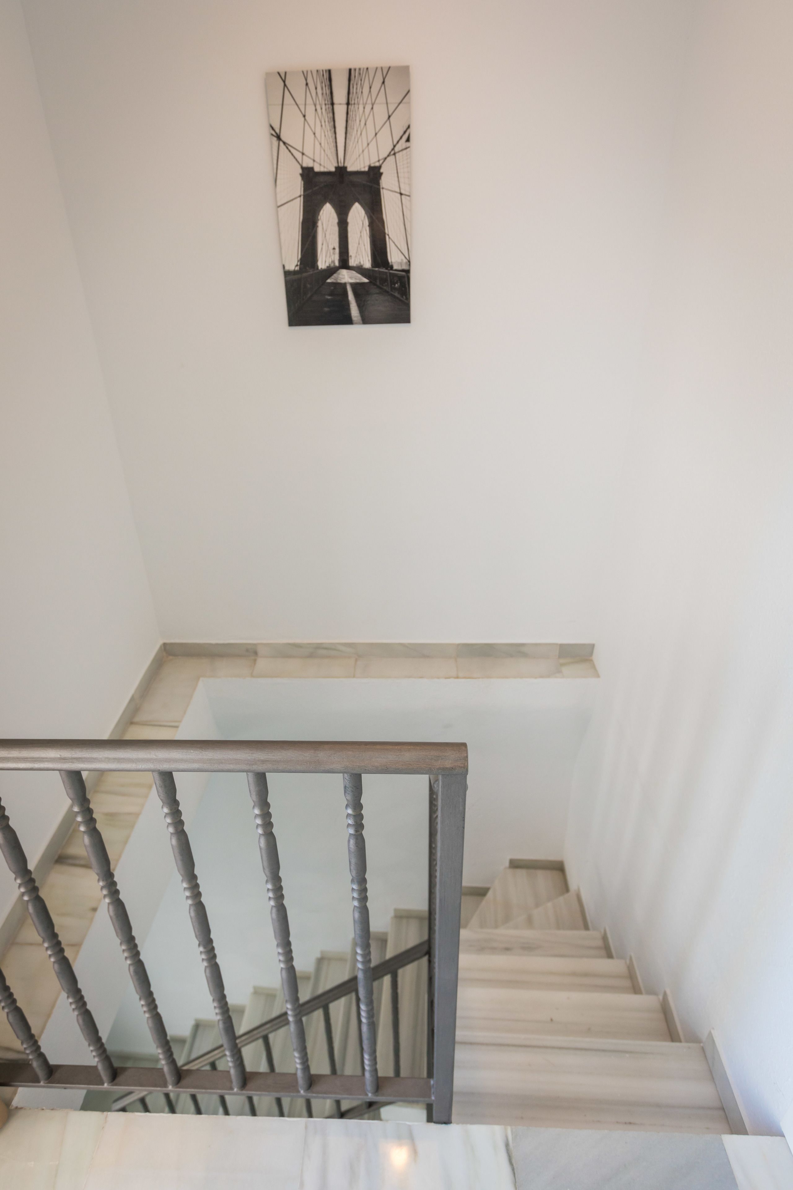 A staircase with a wooden handrail and a black and white artwork above it.